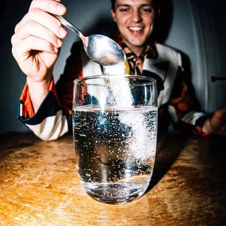Mann gibt Elektrolytpulver in Wasserglas