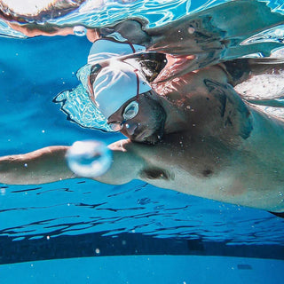 Mann schwimmt im Schwimmbad mit Schwimmbrille und -Kappe