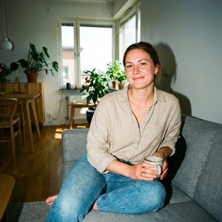 Frau sitzt mit Tasse auf Sofa