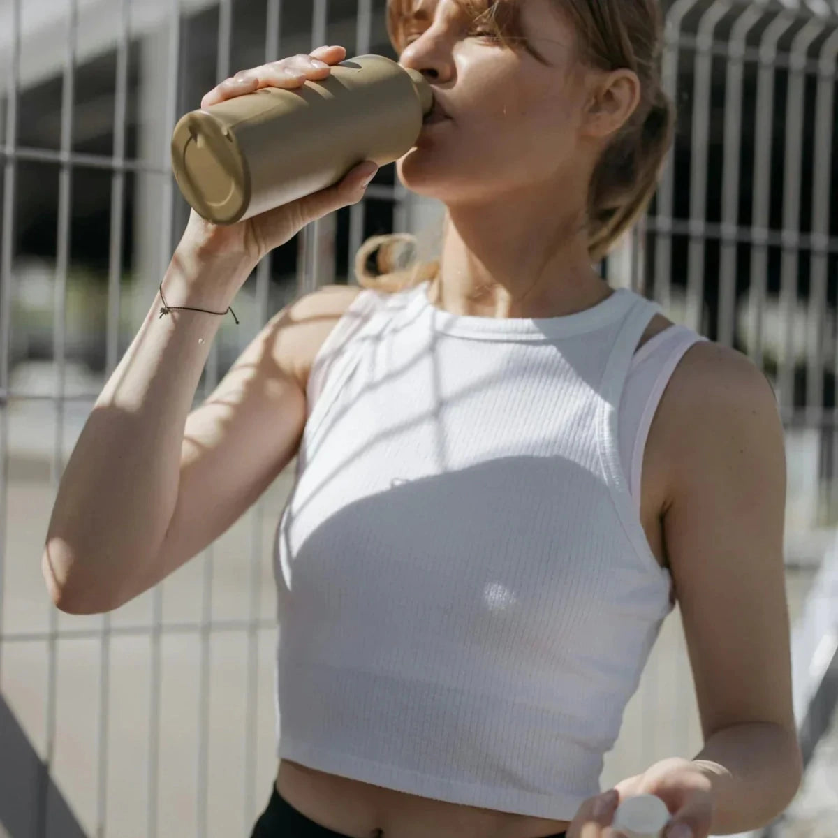 Idratazione Creatina: Donna beve durante lo sport