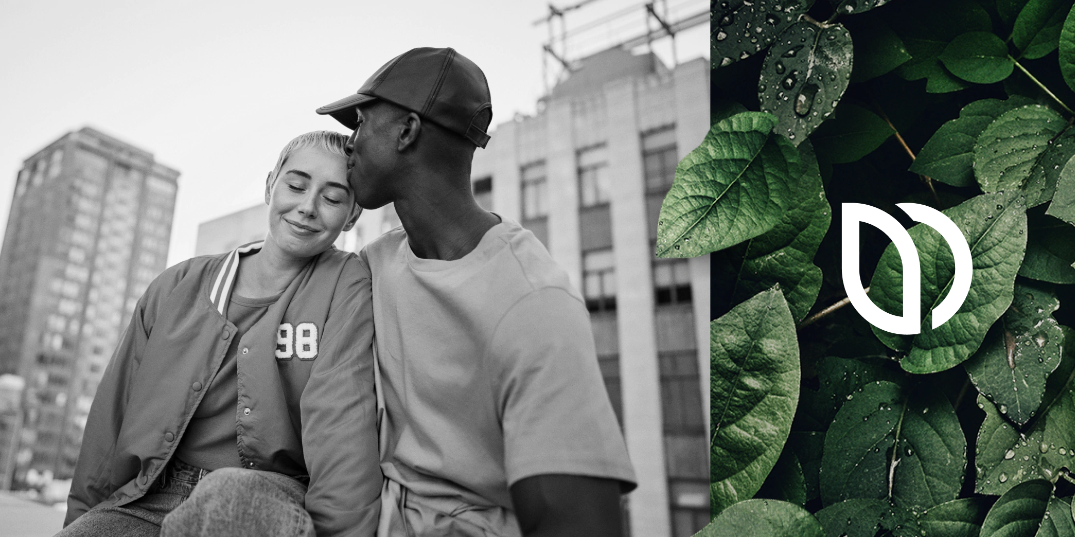 Ein junges Paar sitzt eng beieinander auf einem Stadtdach; der Mann küsst die Schläfe der Frau. Rechts sind grüne Blätter mit Wassertropfen und ein weißes abstraktes Logo zu sehen.