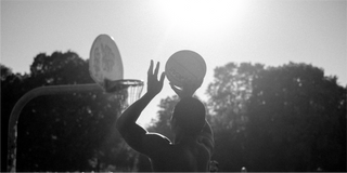 Un uomo prende un frisbee su un campo da basket, circondato da elementi naturali.