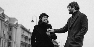 Una foto in bianco e nero di un uomo e una donna che si tengono per mano, catturando la loro connessione in mezzo agli elementi naturali.