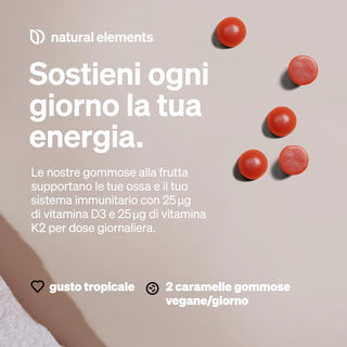 Un set di sei caramelle gommose rotonde e rosse su una superficie beige con testo in italiano che promuove caramelle gommose alla frutta contenenti Vitamina D3 e K2 per l'energia quotidiana, al gusto tropicale e vegane, due al giorno.