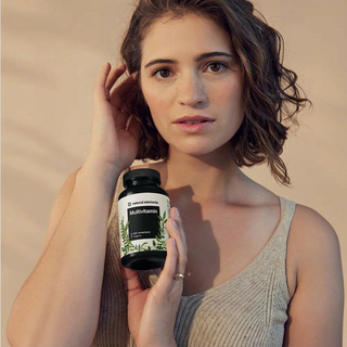 Eine Frau in einem beigen Tank-Top hält eine "Multivitamin"-Flasche von "mindful elements", die natürliche Elemente enthält.