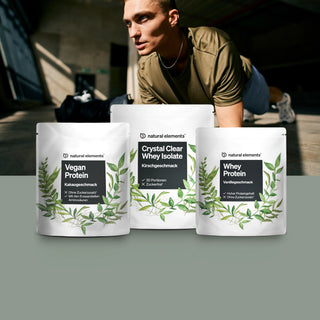Ein Mann trainiert in der Halle hinter drei Beuteln Proteinpulver mit der Aufschrift „Vegan Protein“, „Crystal Clear Whey Isolate“ und „Whey Protein“ der Marke Natural Elements.