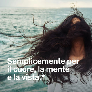 Eine Frau mit langen dunklen Haaren steht, ihre Haare verdecken ihr Gesicht. Der italienische Text lautet: "Semplicemente per il cuore, la mente e la vista.*".