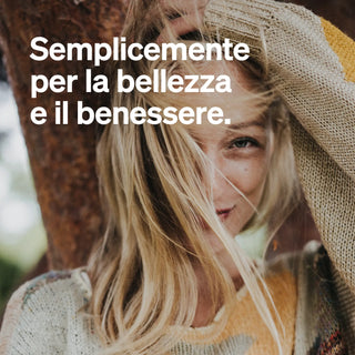 Eine Frau in einem Strickpullover lächelt, während sie ihr Haar hält, mit italienischem Text überlagert: "Semplicemente per la bellezza e il benessere.