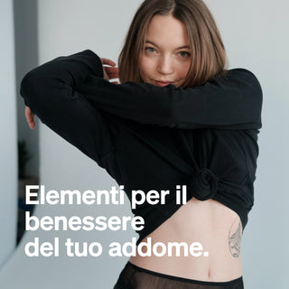 Eine Frau in einem schwarzen langärmeligen Oberteil hebt ihr Hemd und zeigt ihre Taille und ihr Tattoo. Ein eleganter italienischer Text überlagert das Bild.