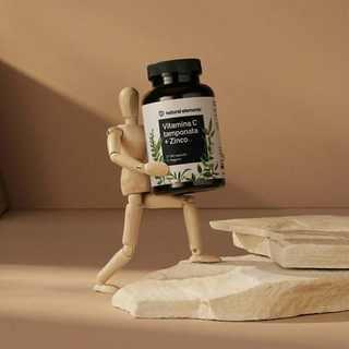 Eine hölzerne Schaufensterpuppe hält eine große Flasche mit der Aufschrift "Vitamina C tamponata + Zinco" von Natural Elements.