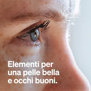 Nahaufnahme von Auge und Wange einer Person mit sichtbaren Wimpern und Hautstruktur. Italienischer Text: "Elementi naturali per una pelle bella e occhi buoni.