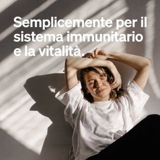 Donna in maglietta bianca seduta a terra alla luce del sole con ombre, accompagnata da un testo italiano sul sistema immunitario e la vitalità.