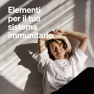 Eine Frau in einem weißen T-Shirt sitzt auf dem Boden. Der Text auf Italienisch lautet: "Elementi naturali per il tuo sistema immunitario".