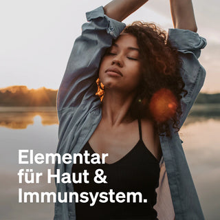 Eine Frau mit geschlossenen Augen und erhobenen Armen. Text: "Elementar für Haut & Immunsystem.